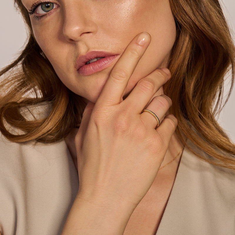 Fijne ring van 14k geel goud op middelvinger met natuurlijke huidtinten.