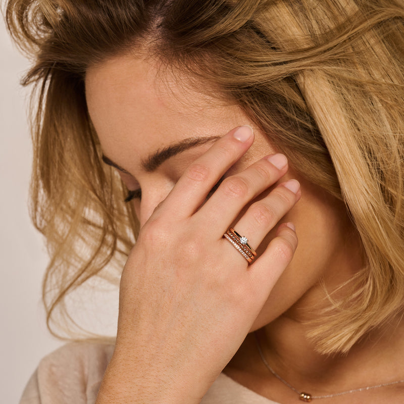 Bicolor ring met 14k rosé goud en 14k wit goud, versierd met zirkonia's, gedragen op vinger.