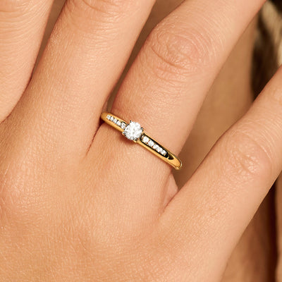 Delicate 14k goud ring met 4 mm zirkonia en rij kleine glinsterende stenen.