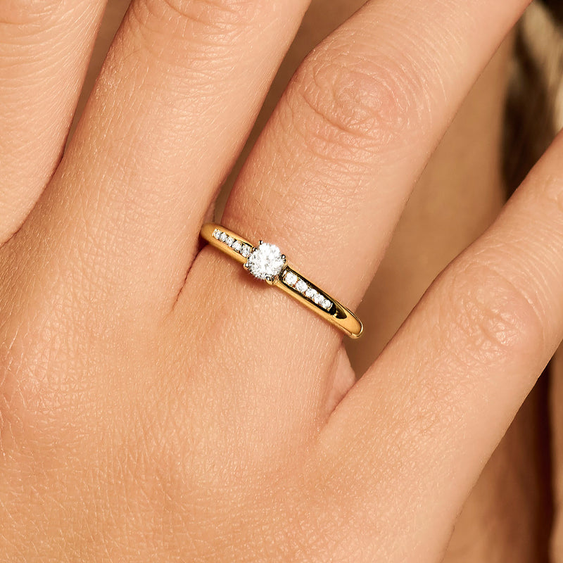 Delicate 14k goud ring met 4 mm zirkonia en rij kleine glinsterende stenen.