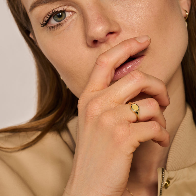 Zegelring van 14k geelgoud met ronde parelmoer steen gedragen aan wijsvinger.