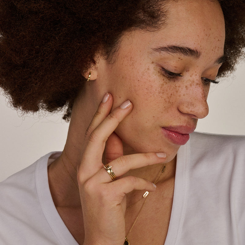 Fijne ketting van 14k geelgoud met subtiele schakelstructuur, gedragen bij witte top.