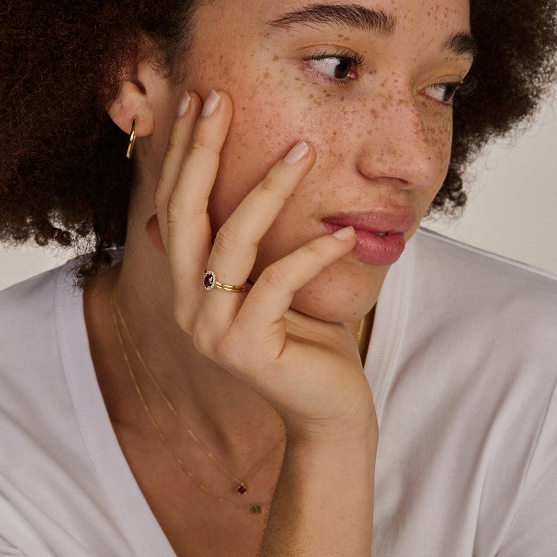 Dunne 14k geelgouden ring met kleine zwarte steen, gedragen aan wijsvinger.