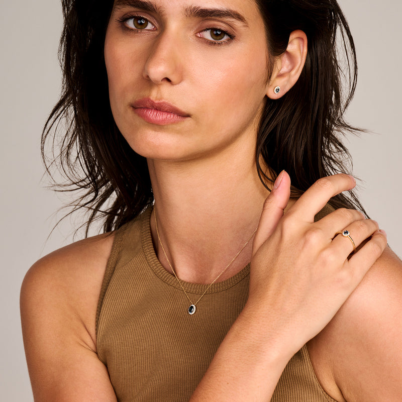 14k geelgouden ring met London blauwe topaas en kleine diamant aan modelhand  .