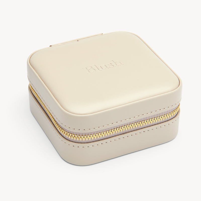 Reiseetui für Schmuck in Grau mit goldfarbenem Reißverschluss und weicher Oberfläche.