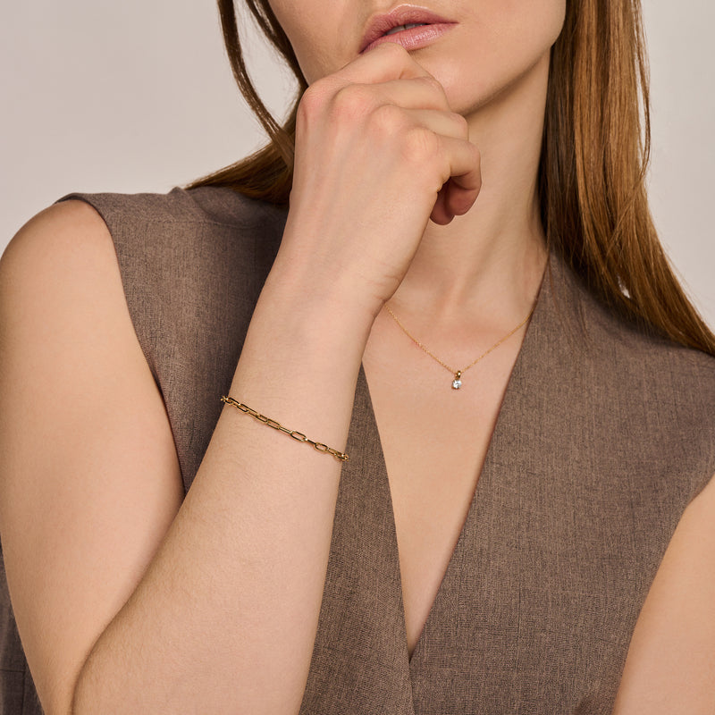 Armband van 14k geelgoud met grove schakels gedragen aan pols.