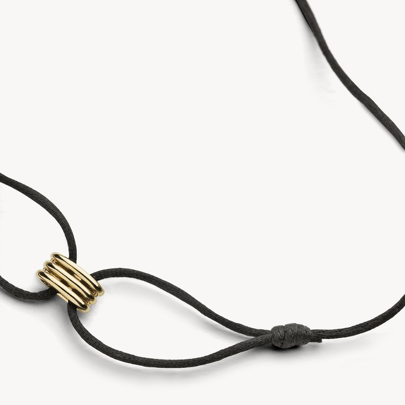 Armband met 14k geel goud detail en zwart zijdekoord, verstelbaar design.