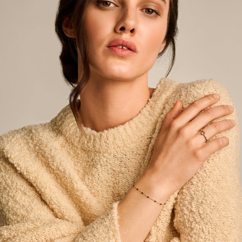 Delicate 14k geelgouden armband met fijne schakels en kleine groene resin kralen.