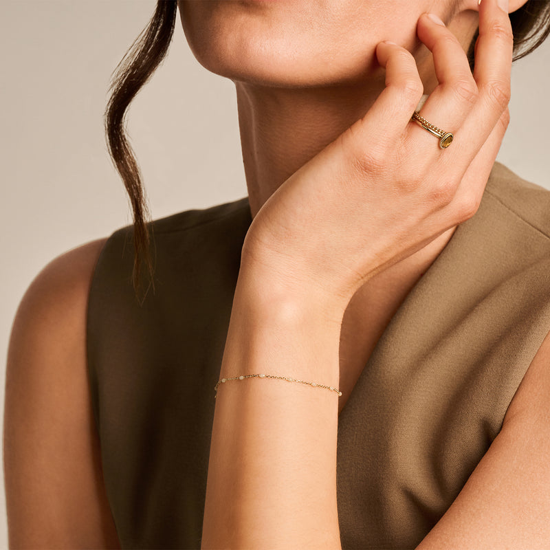 Dunne armband van 14k geel goud met fijne schakels en melkresin detail.