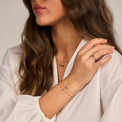 Armband in 14k geelgoud met fijne schakels en rode resin details.