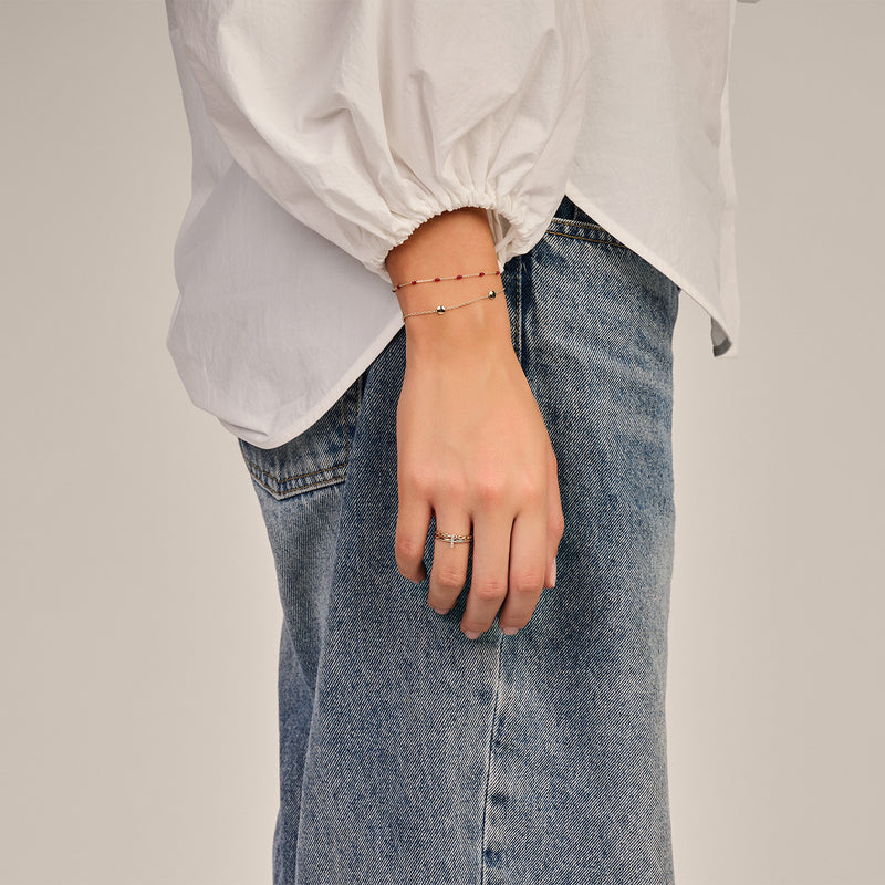 Feiner Gliederarmbänder aus 585er Gelbgold, dezent am Handgelenk mit weißer Bluse und Jeans getragen.