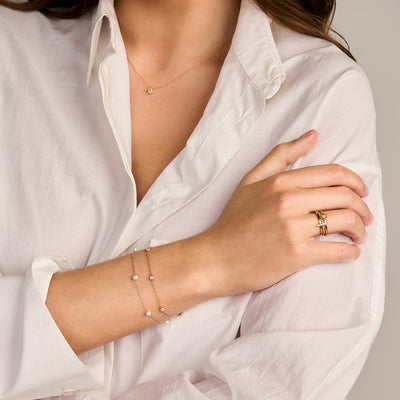 Delicate armband in 14k geelgoud met kleine zirkonia schakels op een pols.