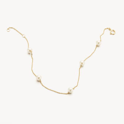 Pearl bracelet with fine links of 14k yellow gold and four white pearls visible.