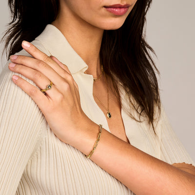 Grof geschakelde armband van 14k geel goud, gedragen aan pols, met warme glans.