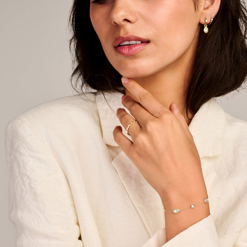 Armband van 14k geelgoud met delicate schakels en kleine parelmoer accenten.