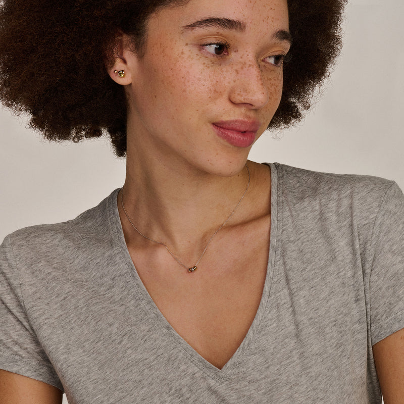 Collier bicolore en Or blanc 14k et rose 14k avec petit Pendentifs, porté sur peau claire.