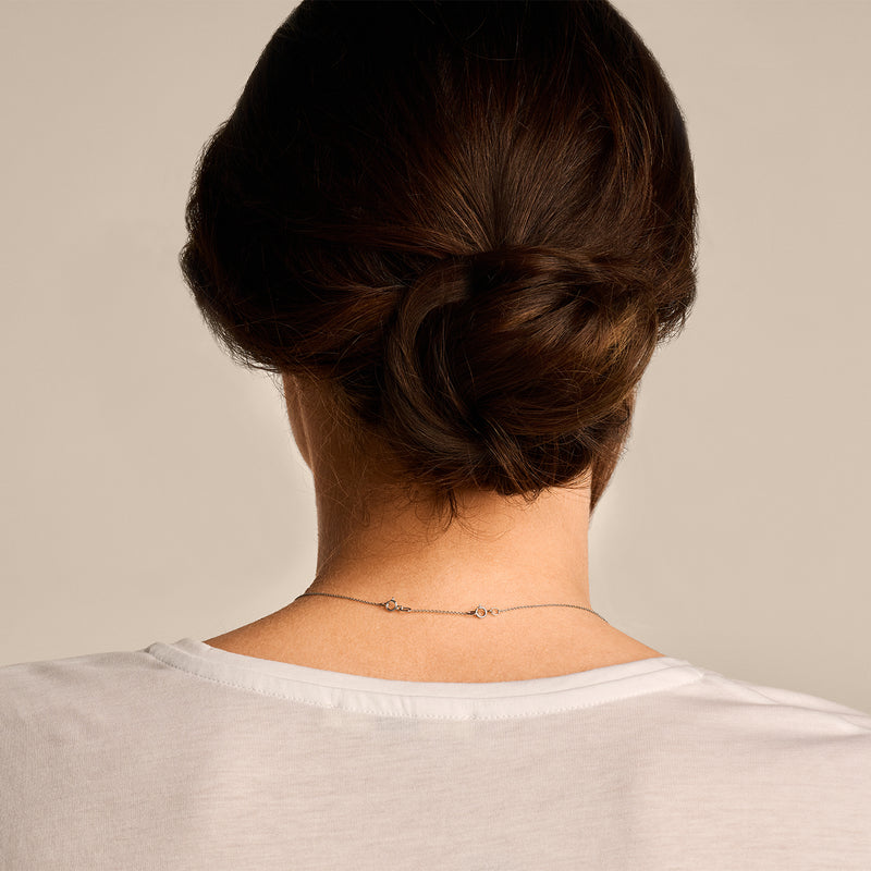 14k wit goud collier verlengstukje met fijne schakels zichtbaar in nek van vrouw.