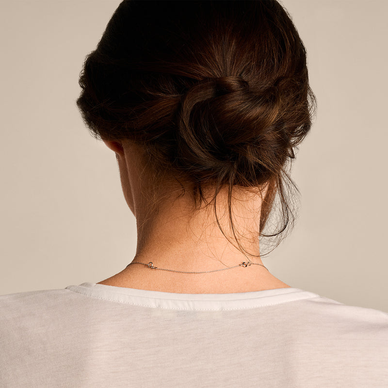 Collier verlengstukje van 14k wit goud met fijne schakels zichtbaar achter de nek.