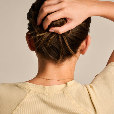 14k Goud ketting verlengstukje fijn schakeltje achter nek op beige achtergrond.