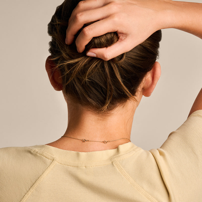 14k Goud ketting verlengstukje fijn schakeltje achter nek op beige achtergrond.