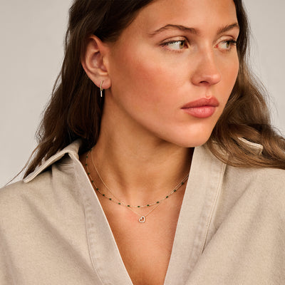 Delicate ketting van 14k geel goud met fijne schakels en groene resin hanger.