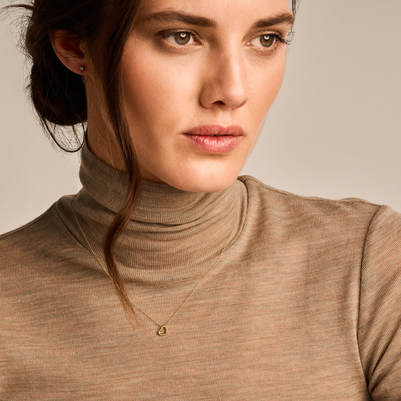 Fijne ketting met klein hartje in 14k geelgoud, subtiel aan modelhals zichtbaar.