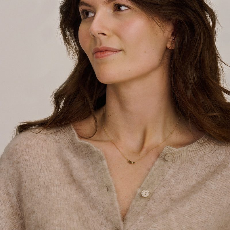 Dunne ketting in 14k geel goud met subtiele schakelstructuur, gedragen door vrouw.