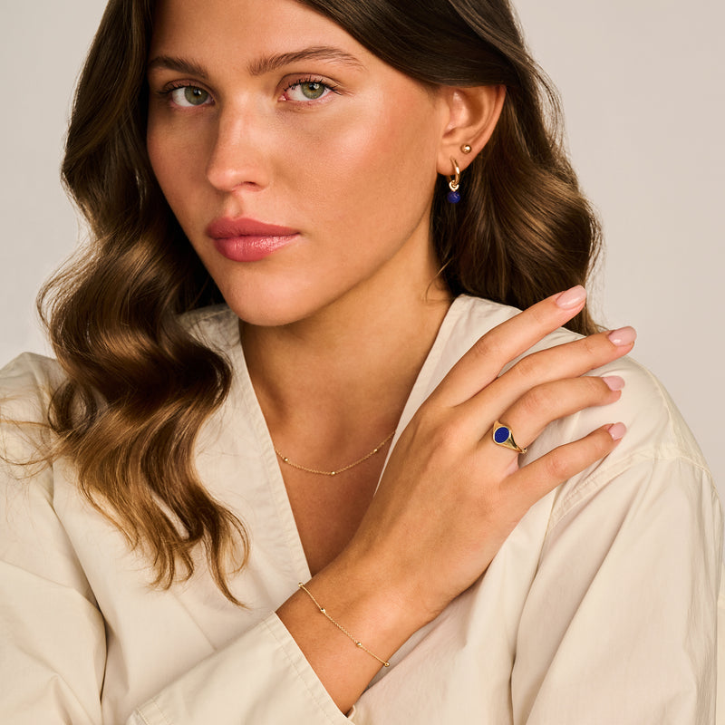 14k Goud fijne schakelketting subtiel gedragen bij beige blouse.