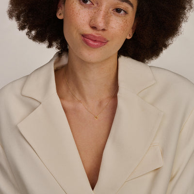 Fijne ketting van 14k geel goud met subtiele schakels, gedragen met lichte blazer.