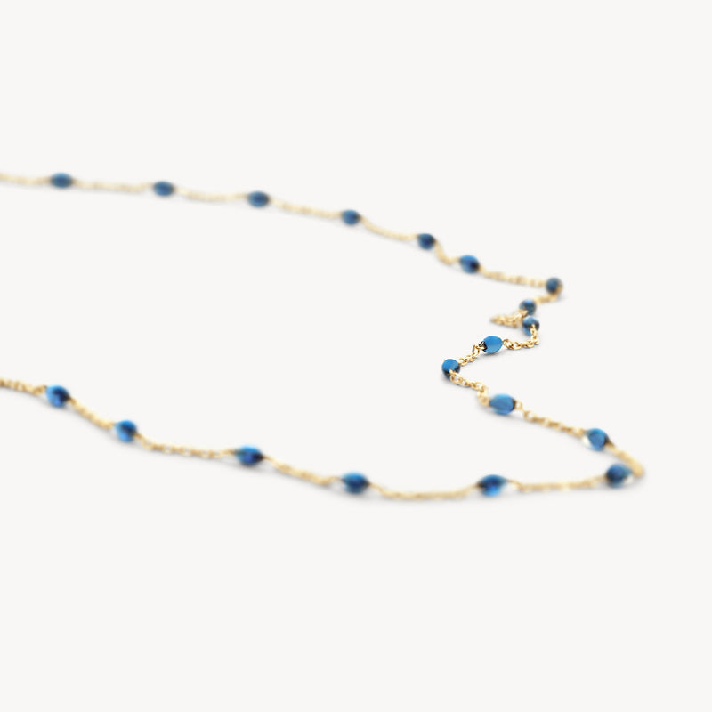 Slanke ketting van 14k geel goud met kleine blauwe resin schakels.