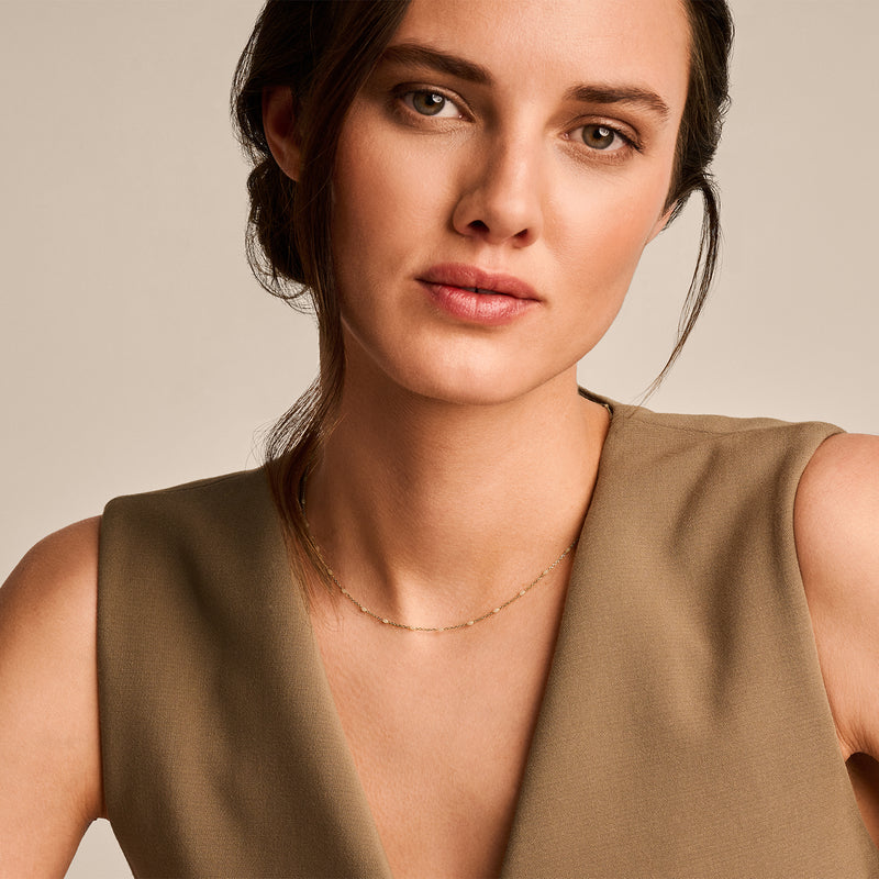 Fijne schakelketting van 14k geelgoud met subtiele glans en melkresin details.