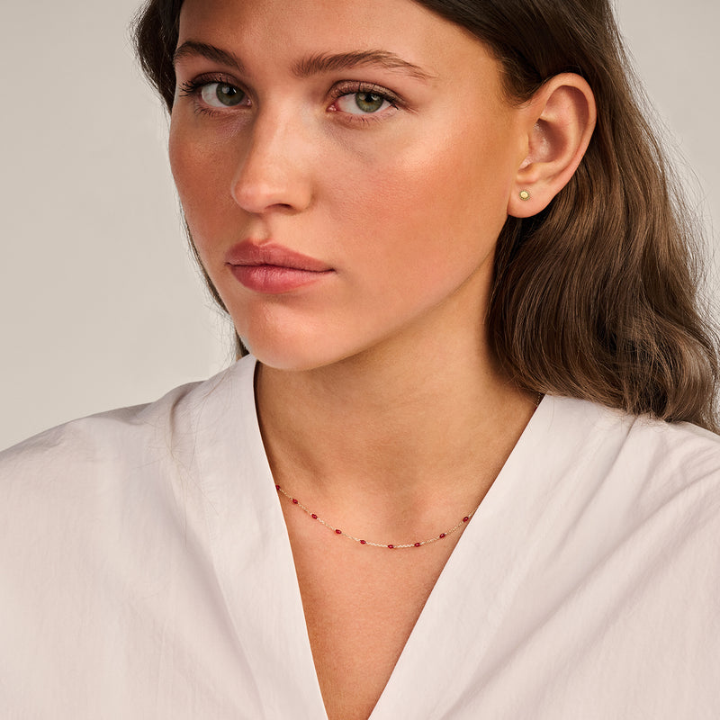 Collier en or jaune 14k avec des maillons fins et des petites perles en résine rouge, effet de scintillement subtil.