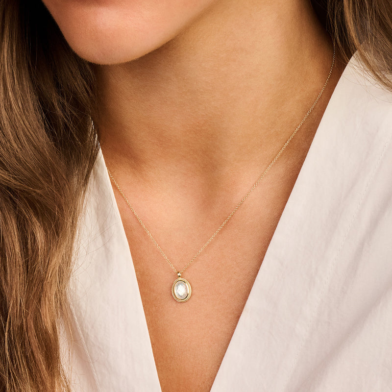 Fijne ketting van 14k goud met ovale parelmoer hanger naast halslijn.