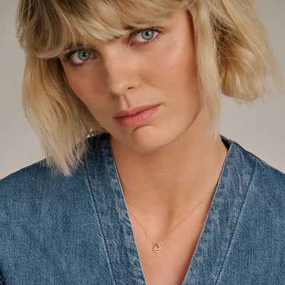 14k goud ketting met fijne schakels en zirkonia hanger gedragen bij een denim blouse.