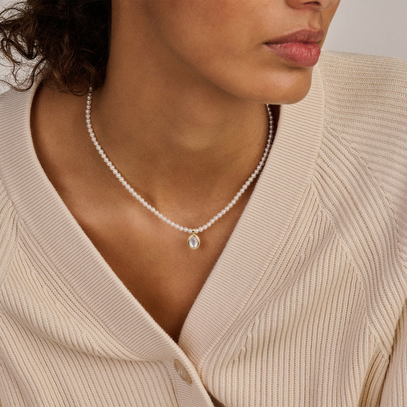 Bicolor goud hanger met parelmoer en bergkristal aan ketting met kleine parels.