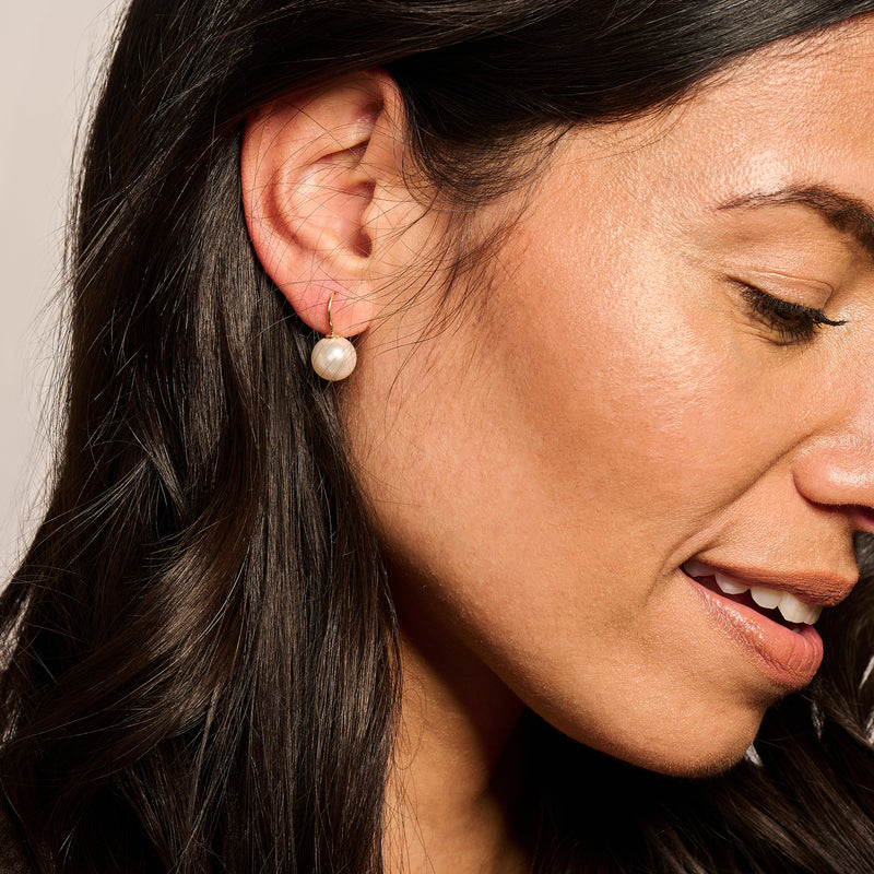 Oorbellen 14k goud met witte Swarovski parel in close-up draagfoto.