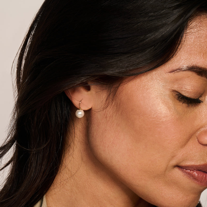 14k geelgouden oorbel met ronde witte Swarovski parel aan oorlel.