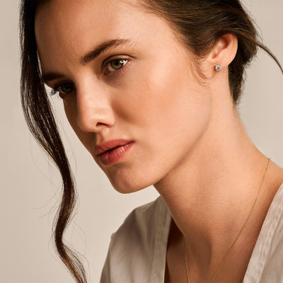 14k geelgouden oorknop met fonkelende zirkonia steen, subtiele glans, close-up bij vrouw.