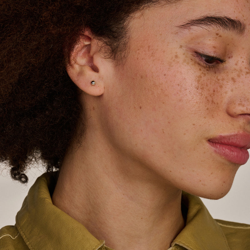 Kleine oorknopjes van 14k wit goud met ronde, gladde afwerking aan het oor.