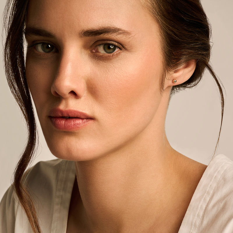 Oorknopje van 14k roségoud met subtiel bicolor goud detail aan oorlel.