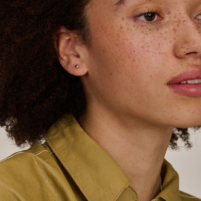 Oorknop van 14k wit goud bicolor met kleine ronde steentjes zichtbaar in oor.