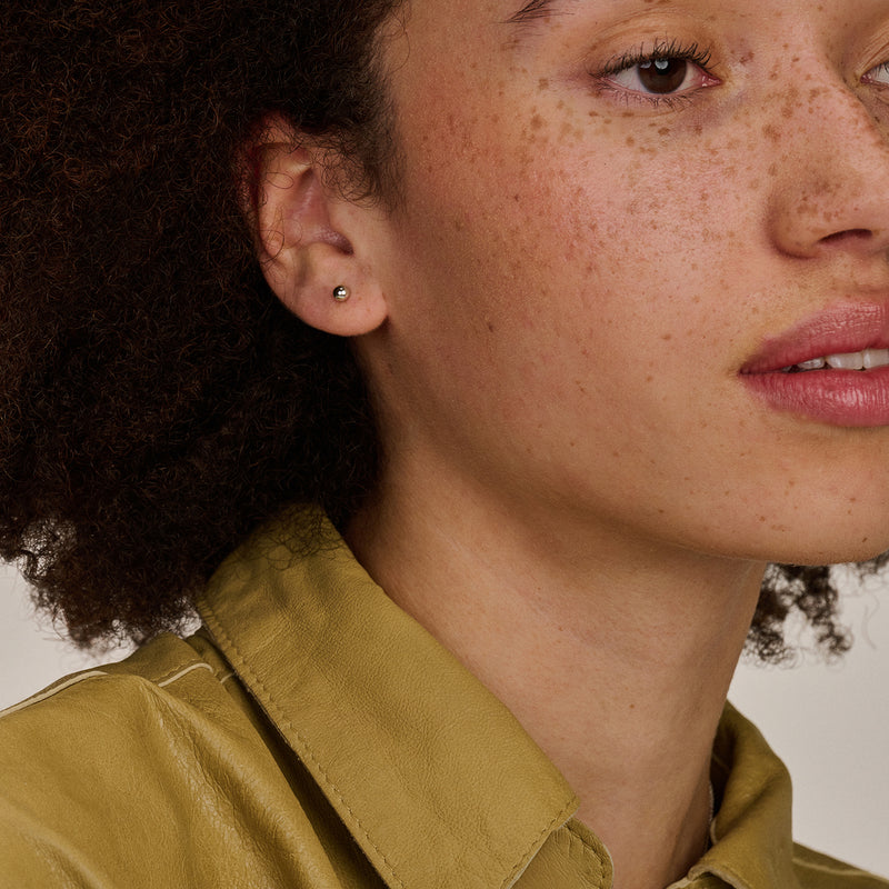 Oorknop van 14k wit goud bicolor met kleine ronde steentjes zichtbaar in oor.