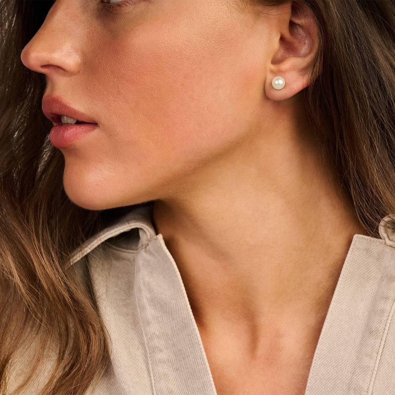 Oorknop met zoetwaterparel in 14k geelgoud aan vrouwenoor.
