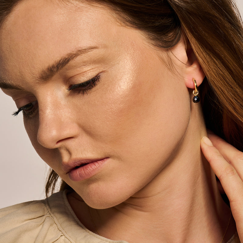 Oorringen van 14k geelgoud met kleine zwarte stenen en stijlvolle haaksluiting.