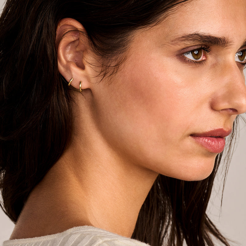 Oorringen 14k goud met minimalistisch design gedragen in oorlel.