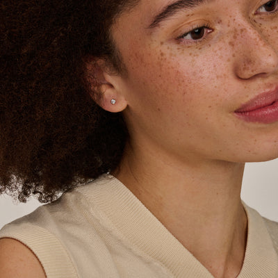 Oorknopje van 14k wit goud met kleine glinsterende zirkonia aan oorlel.