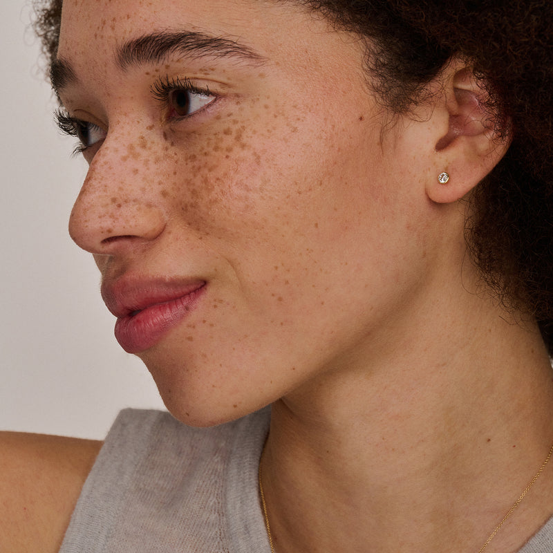 Oorknop in bicolor goud met een witte zirkonia in 14k wit goud setting.