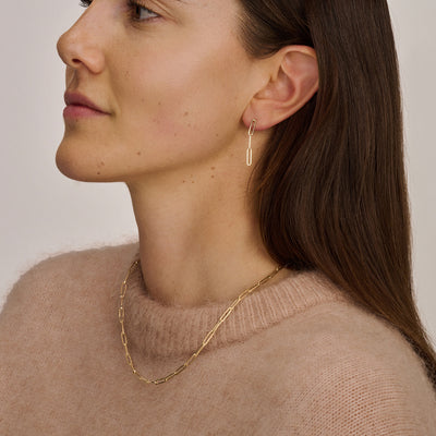 Ketting van 14k goud met grove schakels gedragen met dunne oorbel in 14k rosé goud.