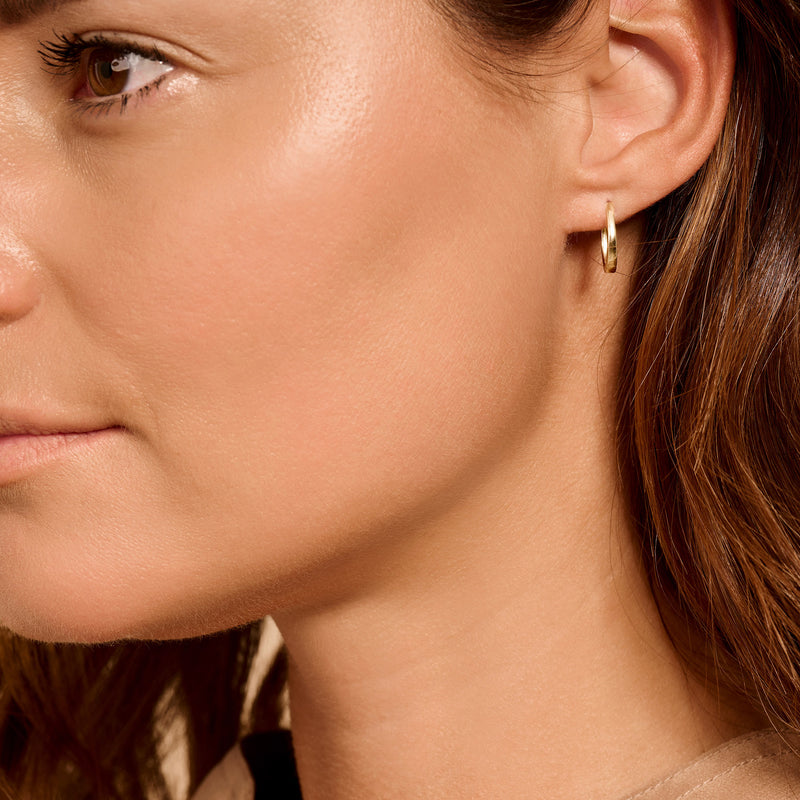 Anneaux d'oreilles en or jaune 14k subtils à l'oreille avec une finition lisse.