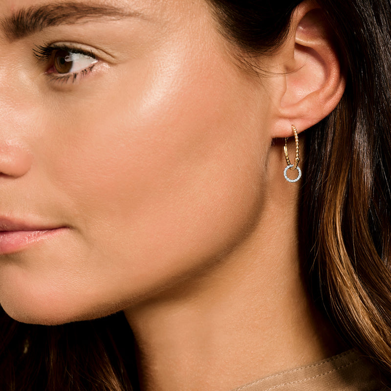 Anneaux d'oreilles en or jaune 14k avec petit pendentif rond au lobe de l'oreille.